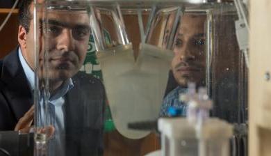 Ali Azadani and fellow researcher viewing a biomedical device in Azadani's lab