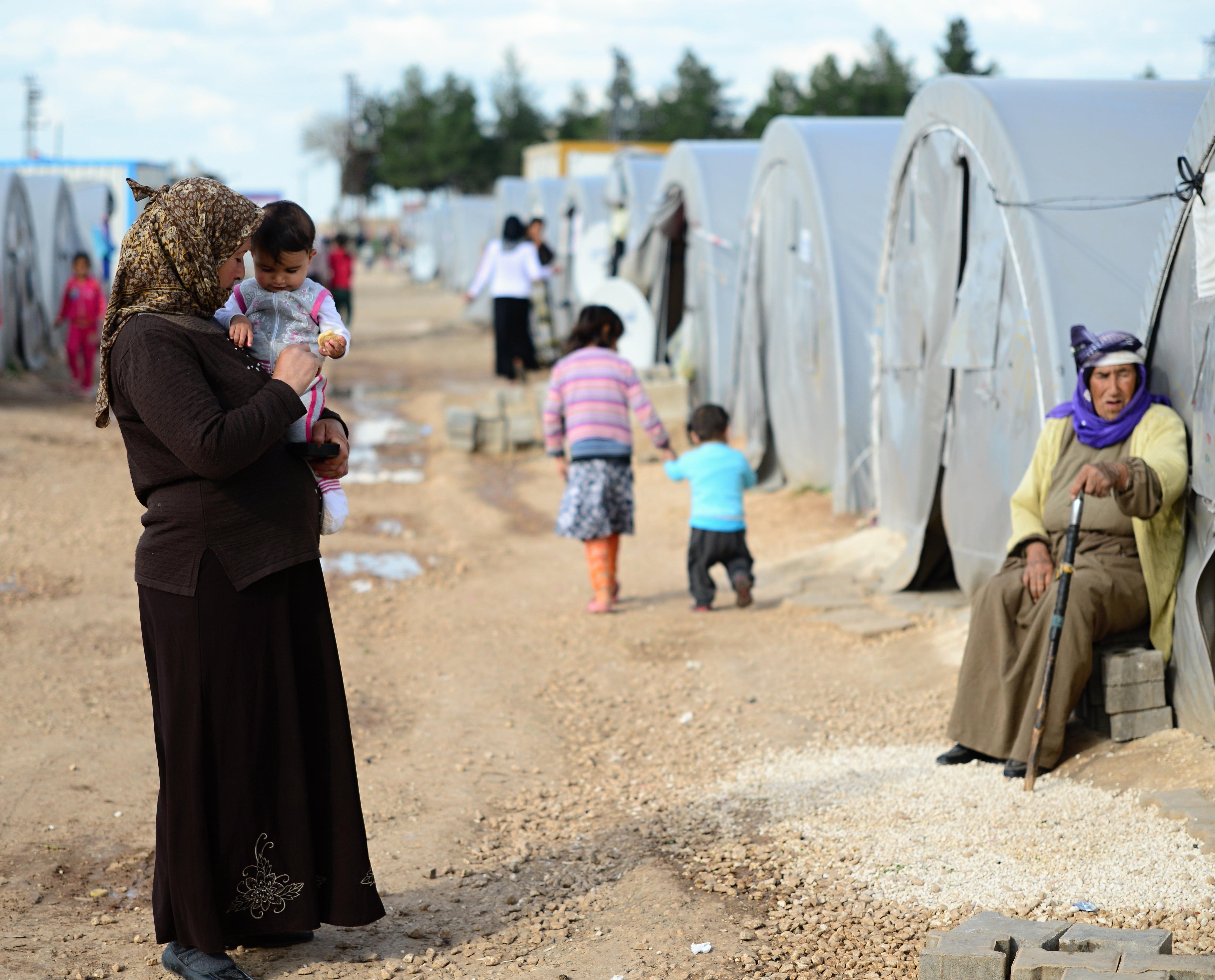一名妇女抱着她的孩子站在土耳其的叙利亚难民营.